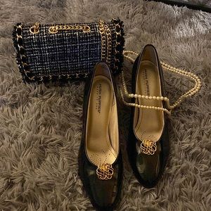 Black heeled shoe. Gold accessory on toe.